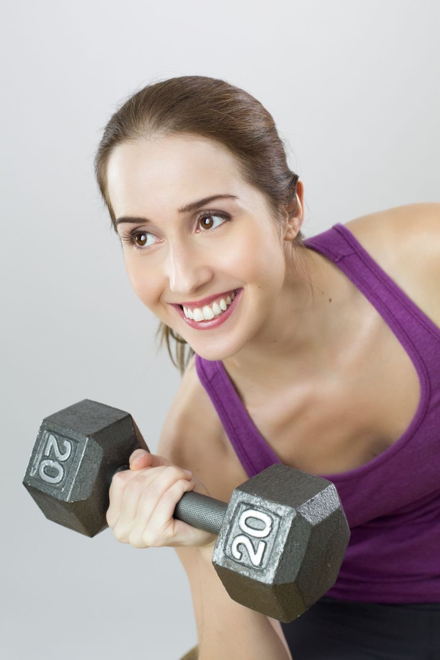Young woman exercises with a dumbbell, showing strength and positivity.